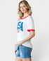 Woman wearing a white t-shirt with 'USA' print and denim shorts on a plain background