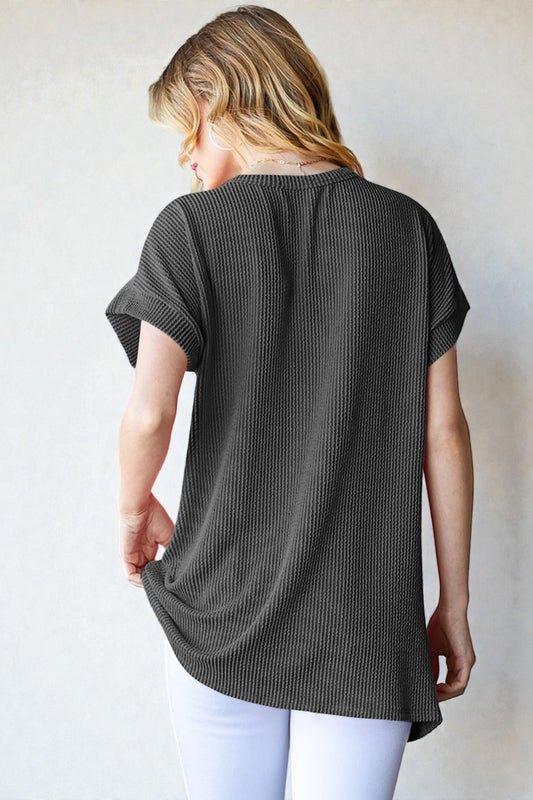 Woman wearing a dark gray textured tunic over white pants against a plain background