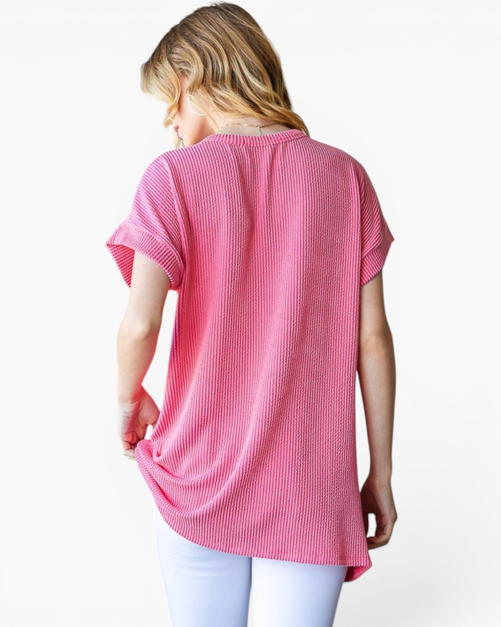 A woman shown from the back wearing a pink short-sleeve waffle-knit top and white pants against a plain white background.