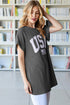 Woman wearing a dark gray t-shirt with 'USA' printed on it in a library setting.