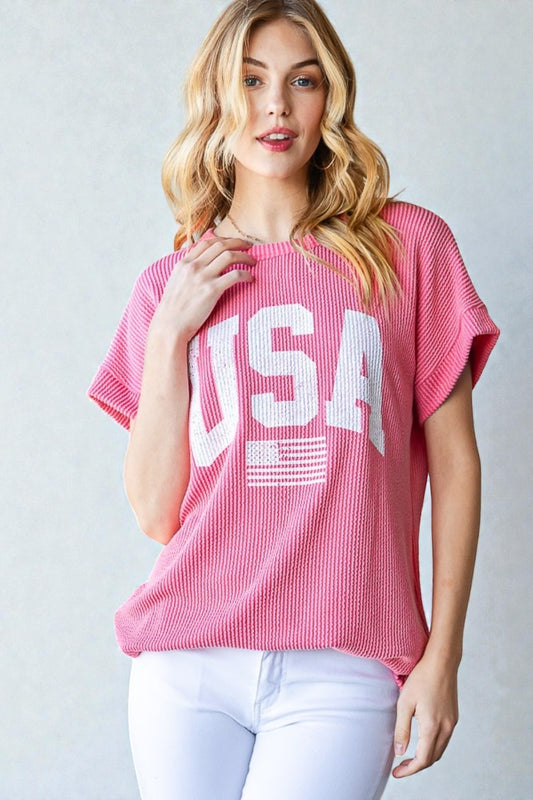 Woman wearing a pink 'USA' t-shirt against a plain background