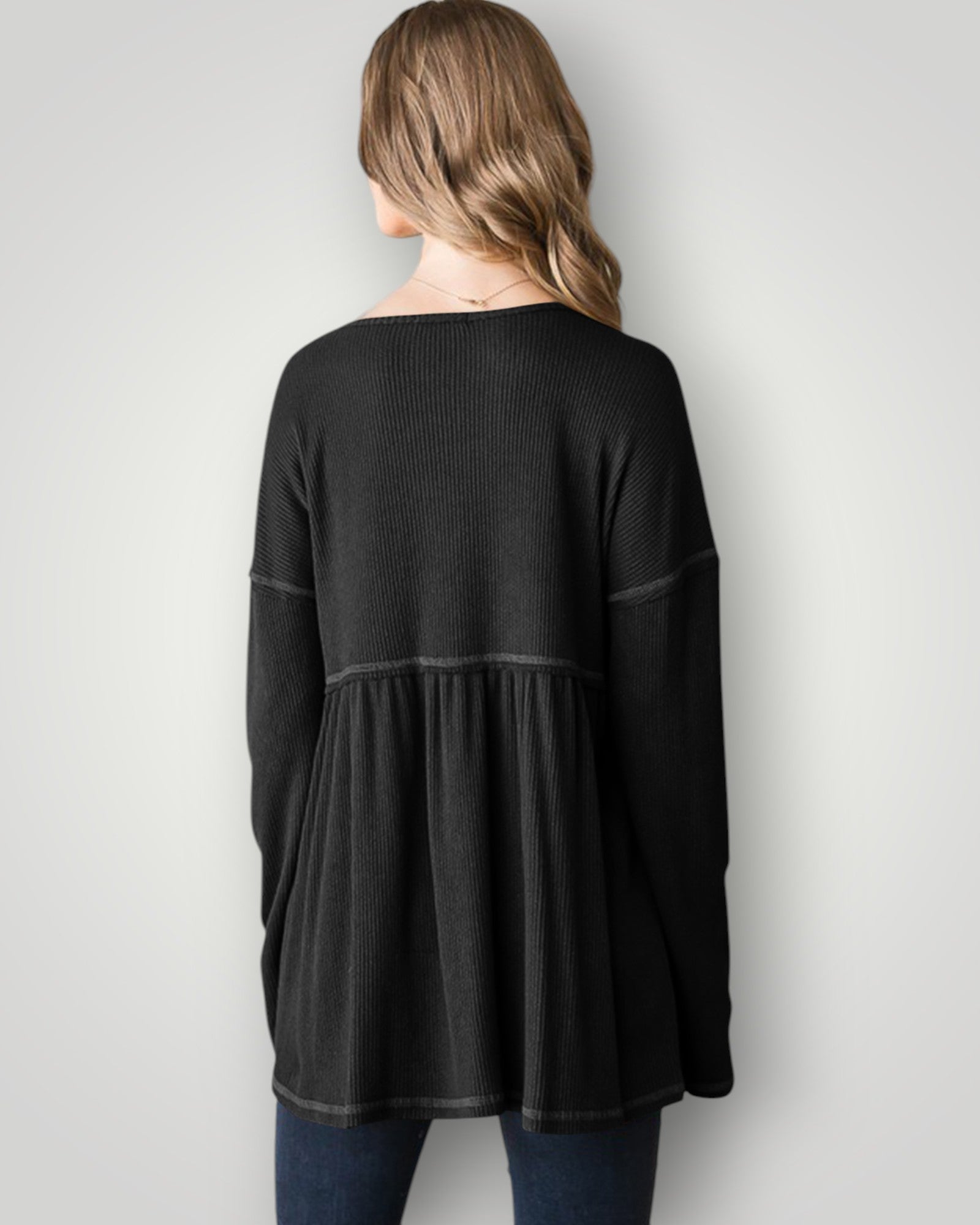 Woman wearing a black long-sleeve top against a plain background