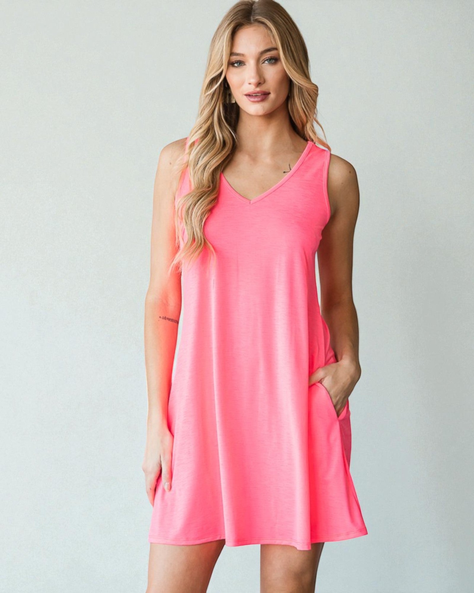 Woman wearing a pink sleeveless dress against a plain background