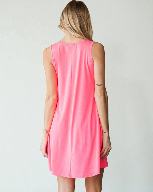 Woman wearing a pink sleeveless dress against a plain background