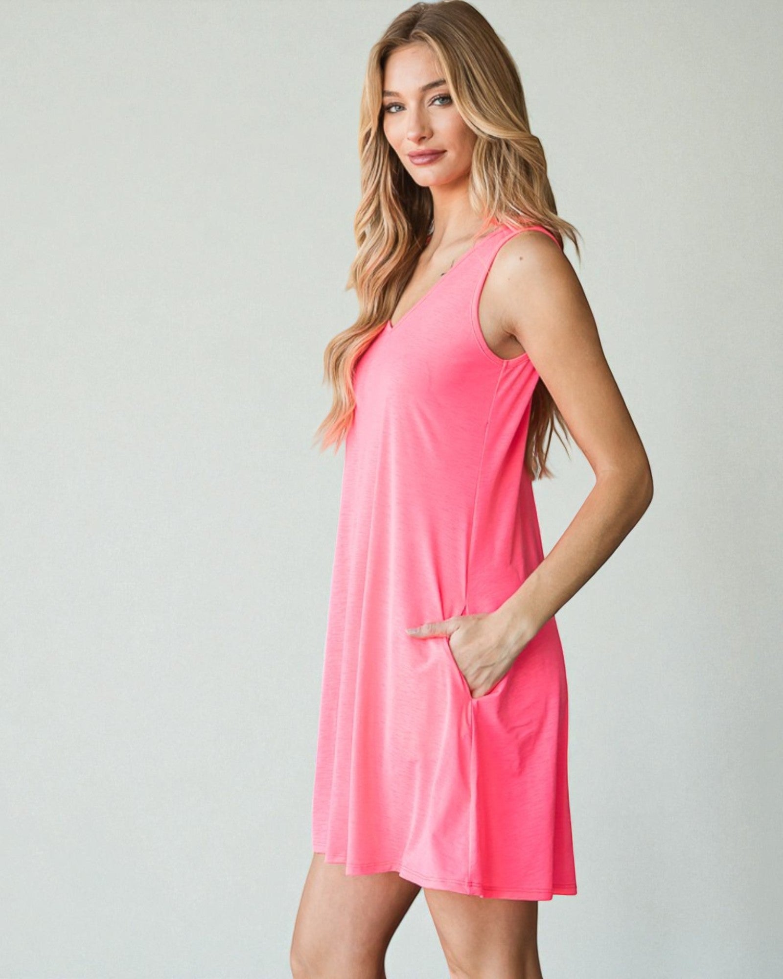 Woman wearing a pink sleeveless dress against a plain background