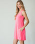 Woman wearing a pink sleeveless dress against a plain background