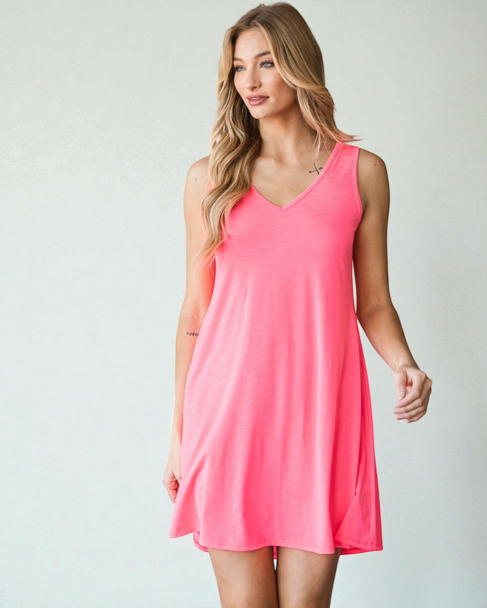 Woman wearing a pink sleeveless dress against a plain background