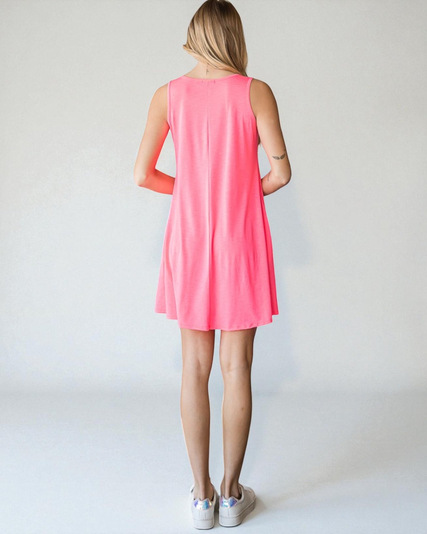 Woman wearing a pink sleeveless dress against a white background