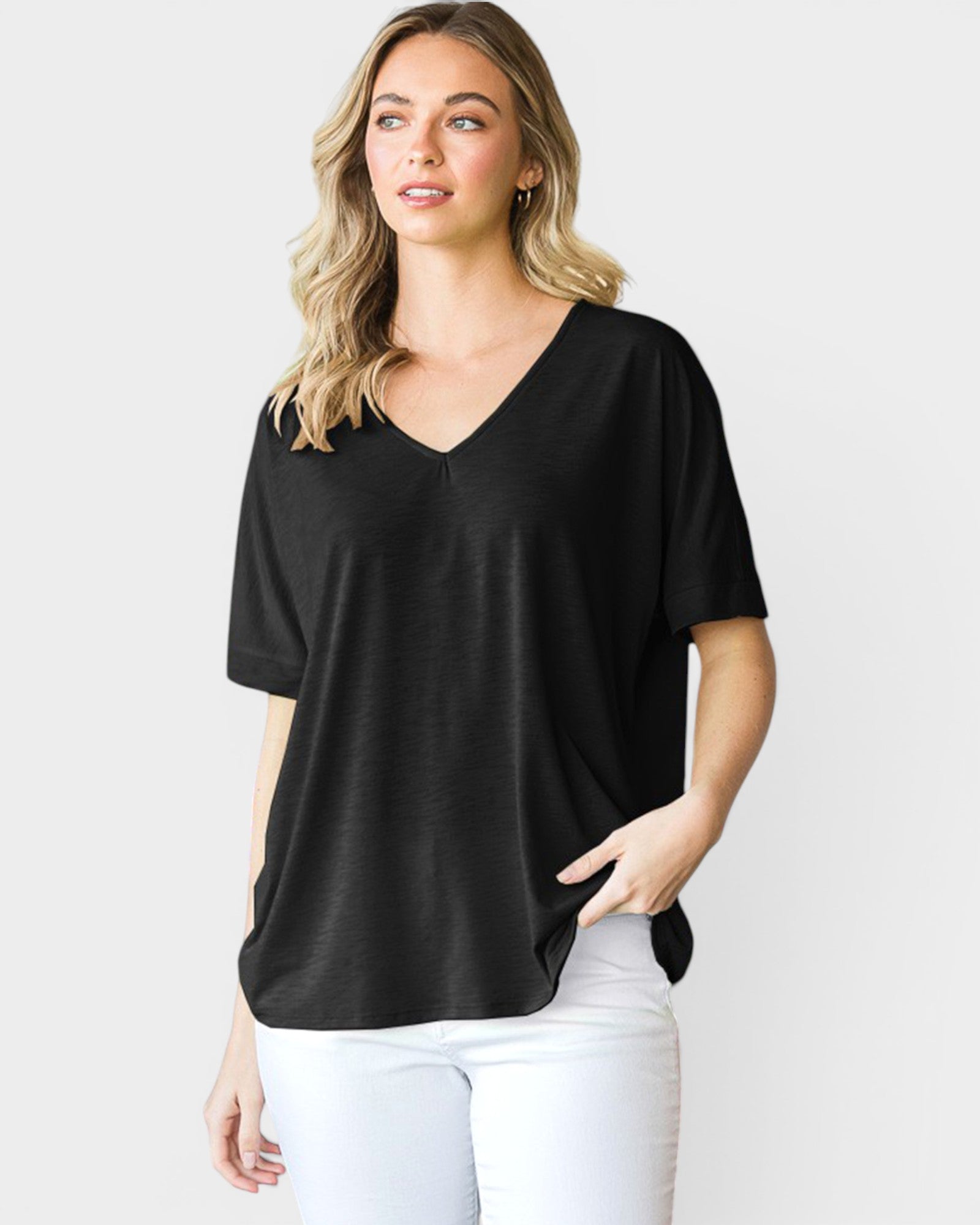 Woman wearing a black V-neck t-shirt and white pants on a light gray background