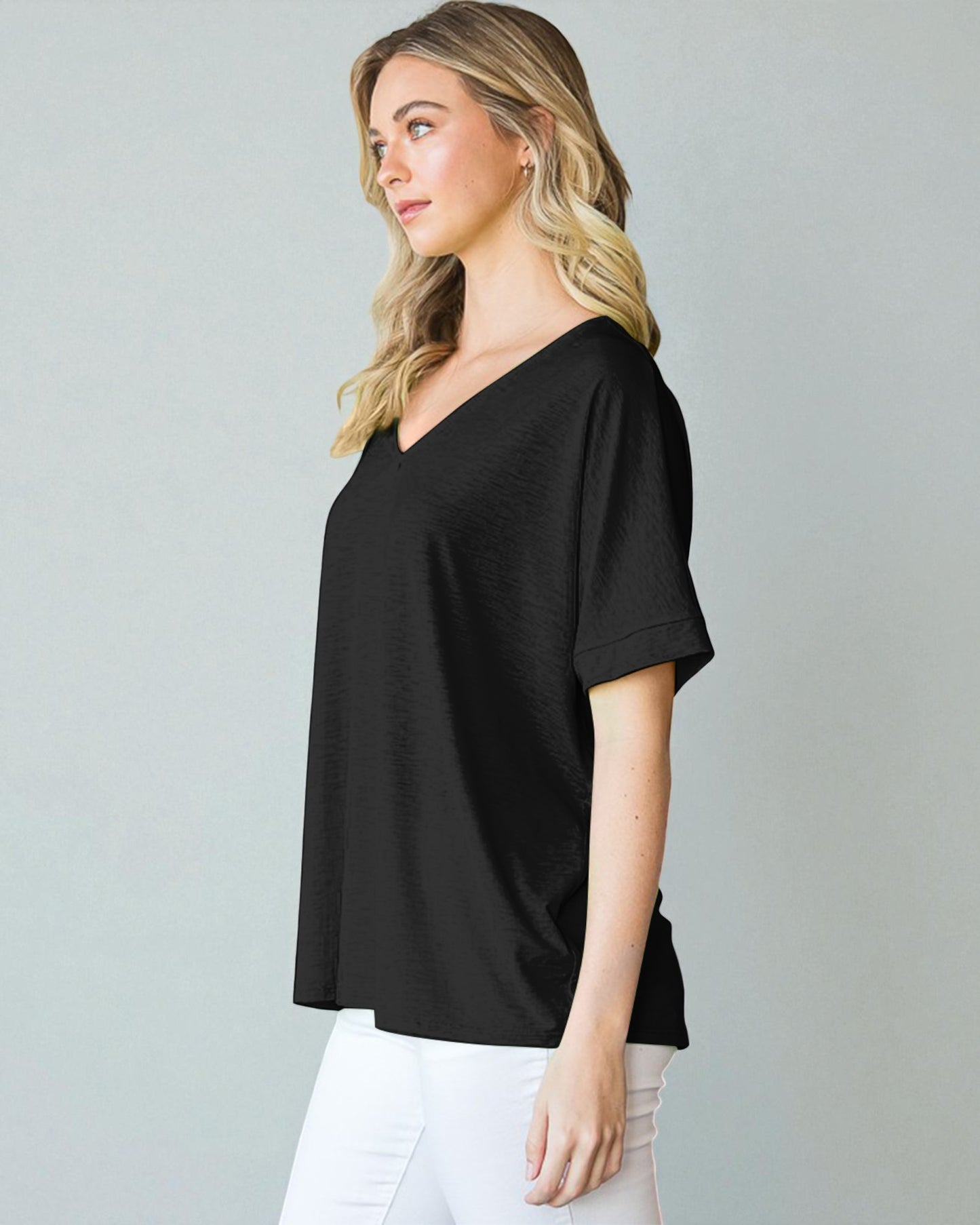 Woman wearing a black V-neck t-shirt against a gray background