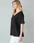 Woman wearing a black V-neck t-shirt against a gray background