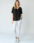 Woman wearing a black t-shirt and white pants on a plain background