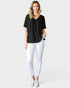 Woman wearing a black t-shirt and white pants on a plain background