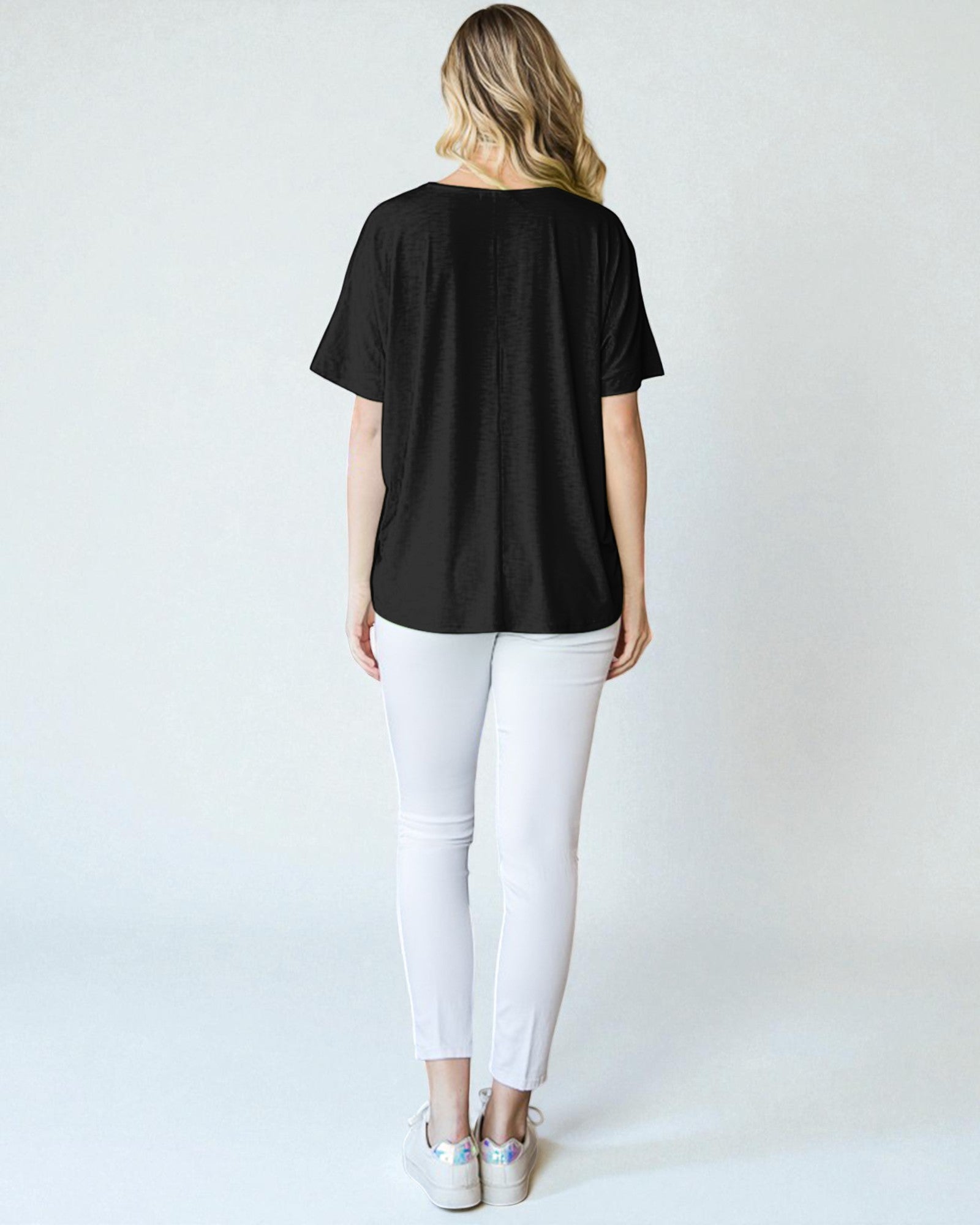 Person wearing a black t-shirt and white pants on a plain background