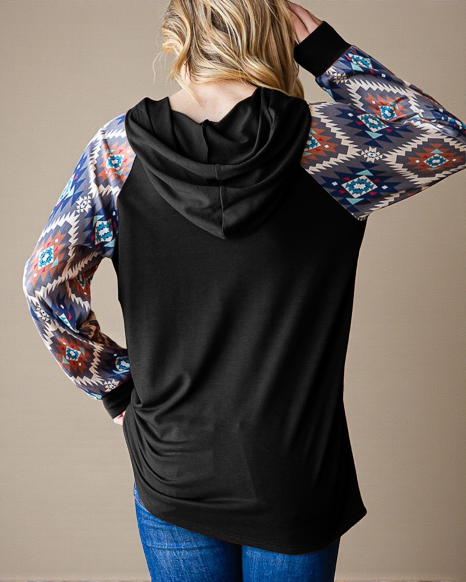 Black hoodie with patterned sleeves worn by a person on a beige background