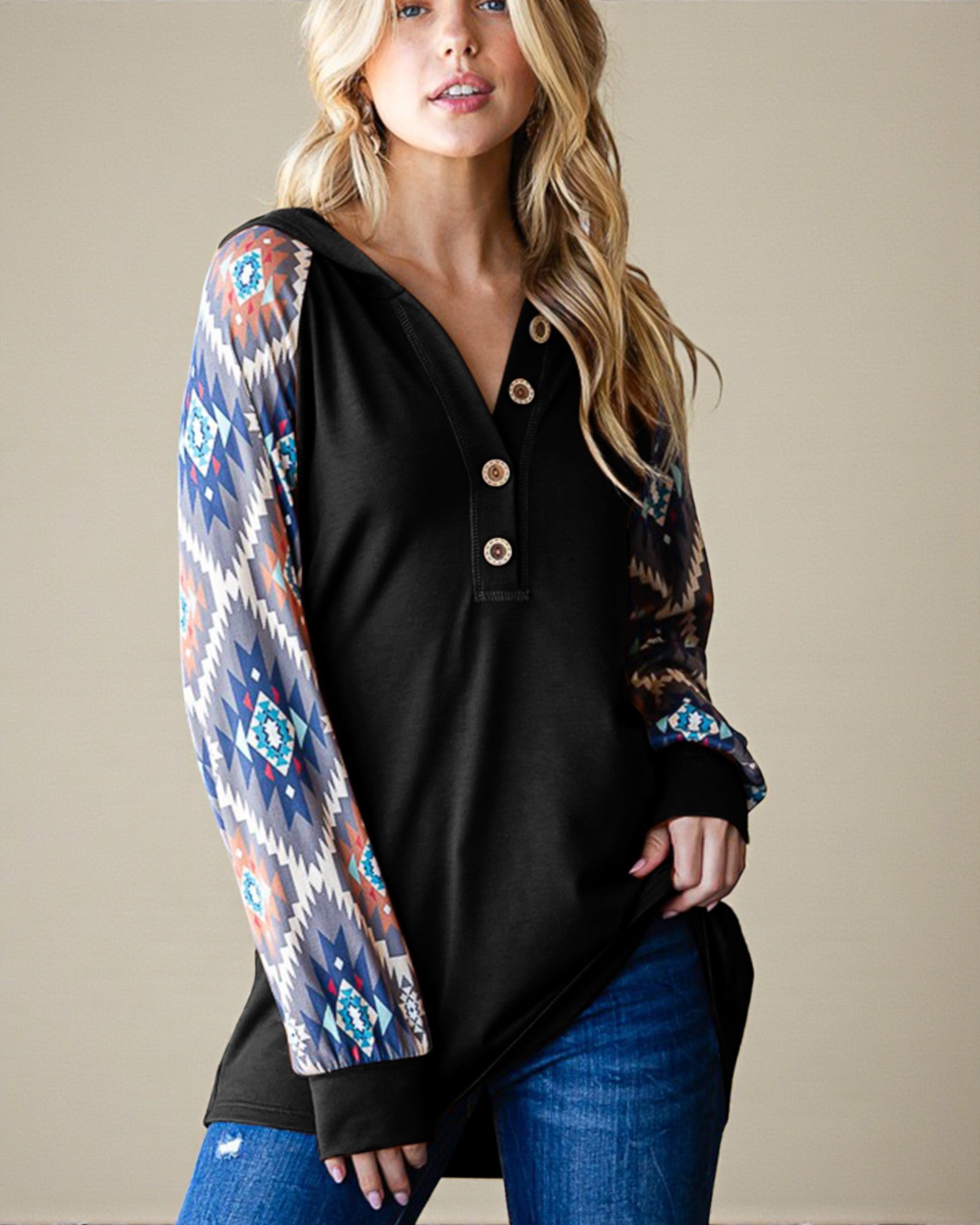 Woman wearing a black top with colorful sleeves against a beige background