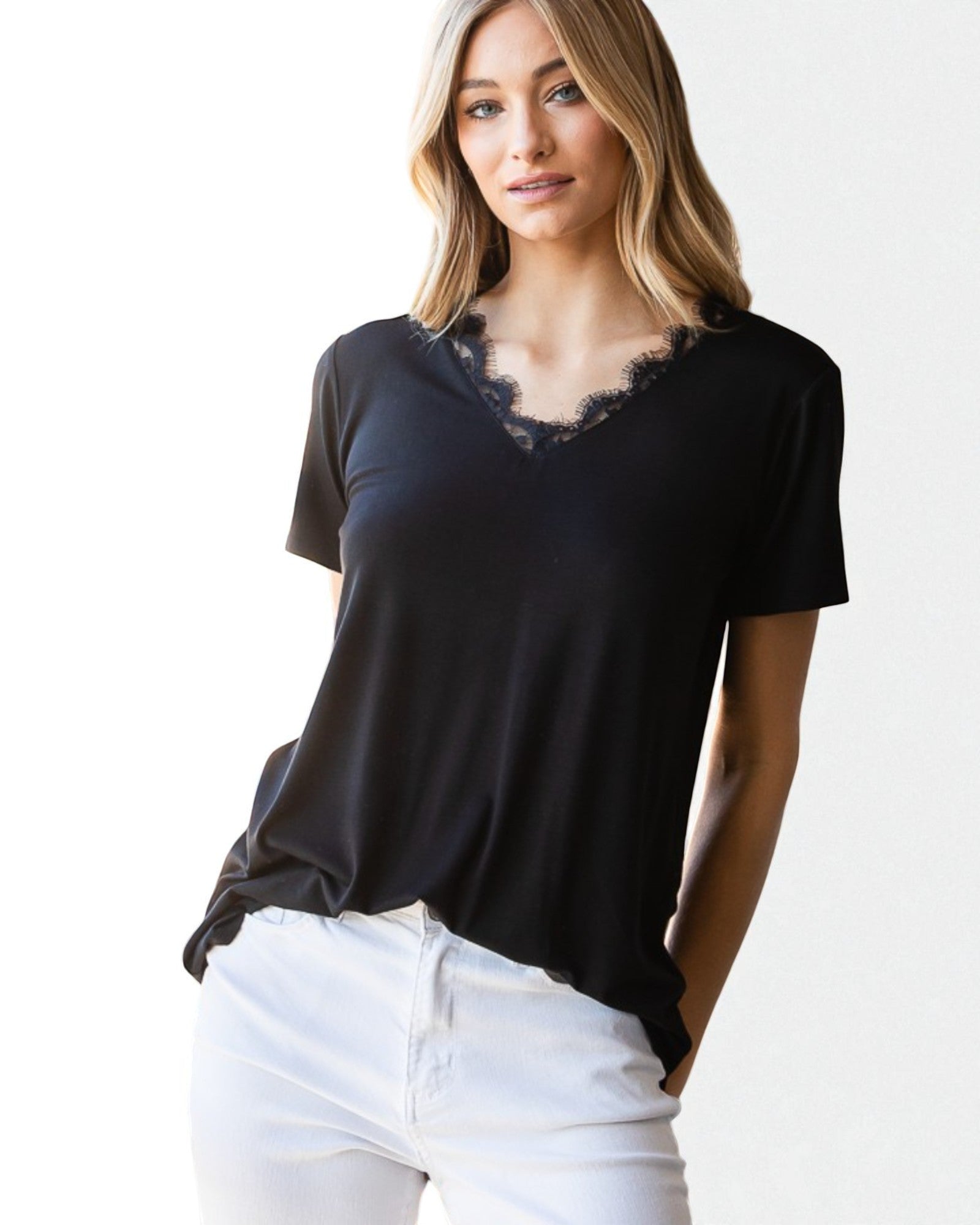 Woman wearing a black t-shirt with a floral neckline and white pants on a white background