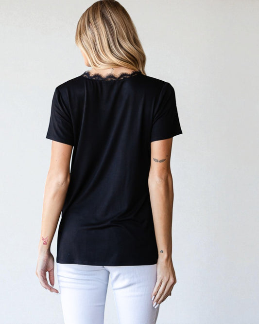 Person wearing a black t-shirt and white pants against a plain background