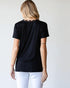 Person wearing a black t-shirt and white pants against a plain background
