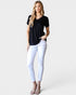 Woman wearing a black top and white pants on a plain background
