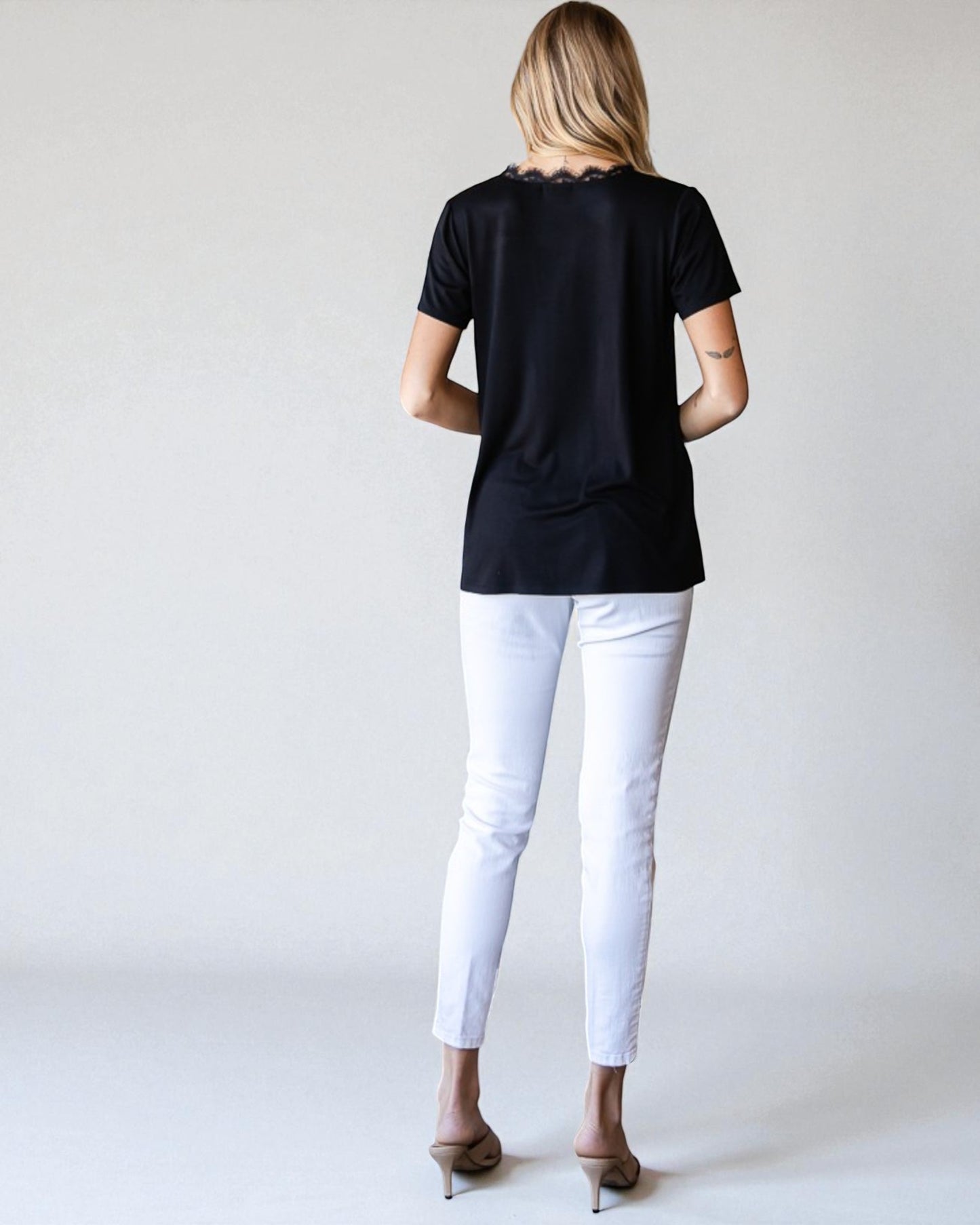 Person wearing a black t-shirt and white pants on a plain background