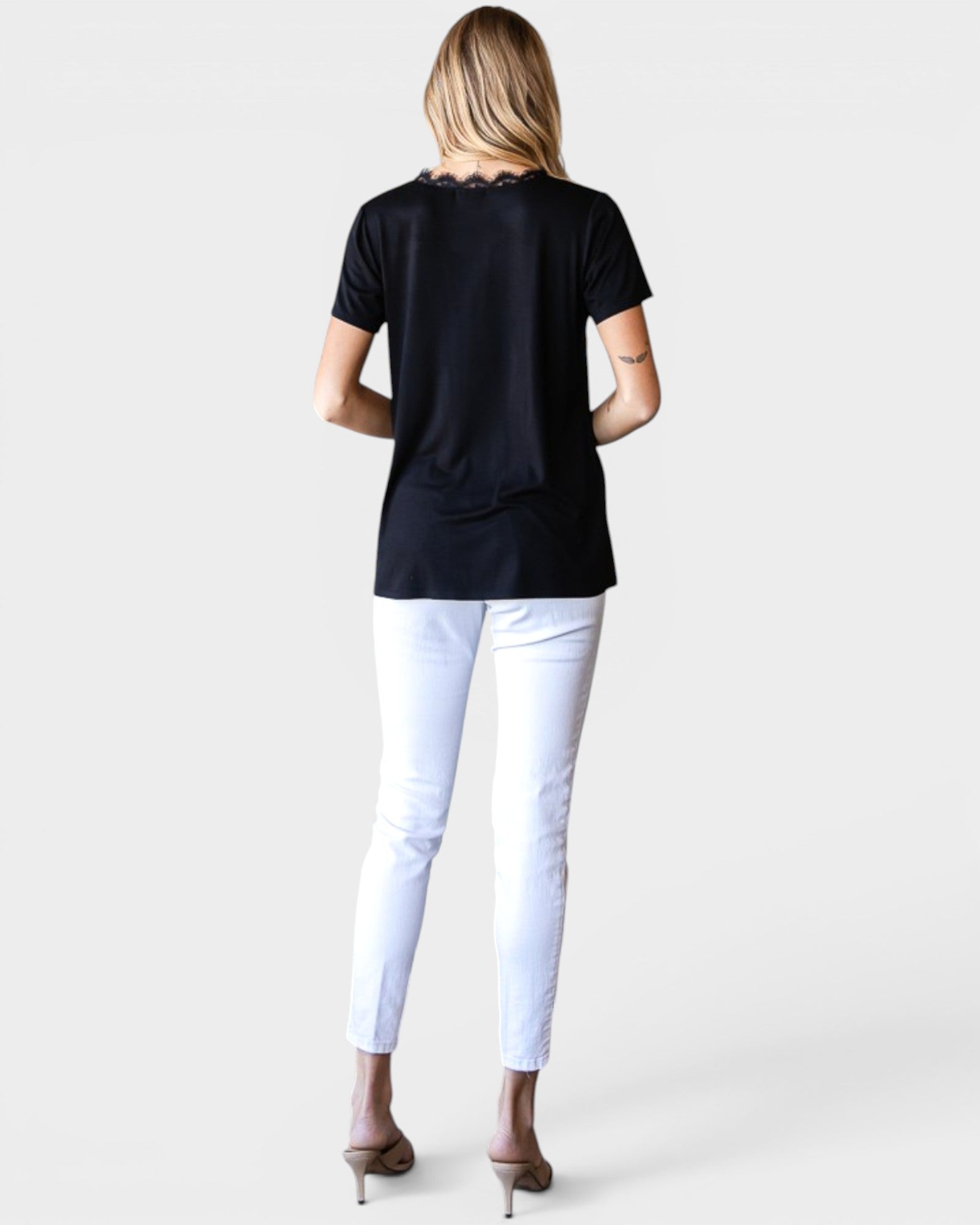 Person wearing a black t-shirt and white pants on a plain background