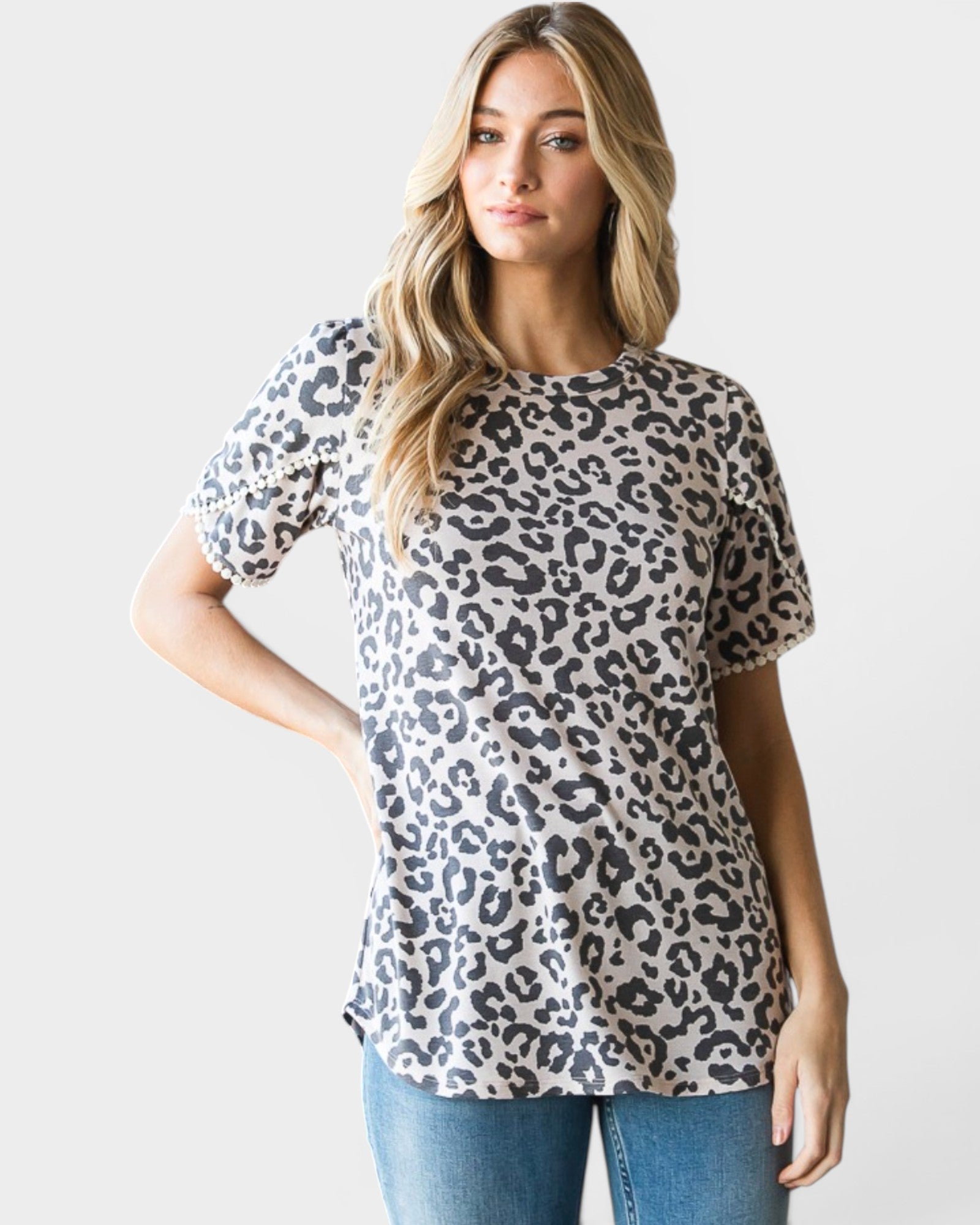 Woman wearing a leopard print top and jeans on a plain background