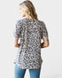 Woman wearing a leopard print top and blue jeans on a white background