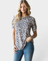 Woman wearing a leopard print top and blue jeans on a plain background