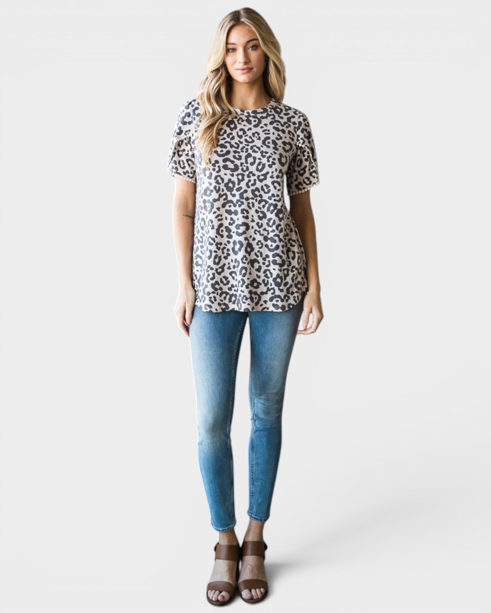 Woman wearing a leopard print top and blue jeans on a white background