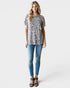 Woman wearing a leopard print top and blue jeans on a white background