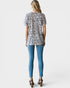 Woman wearing a leopard print top and blue jeans on a white background