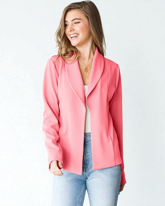 Woman wearing a pink blazer over a white top and blue jeans on a light gray background
