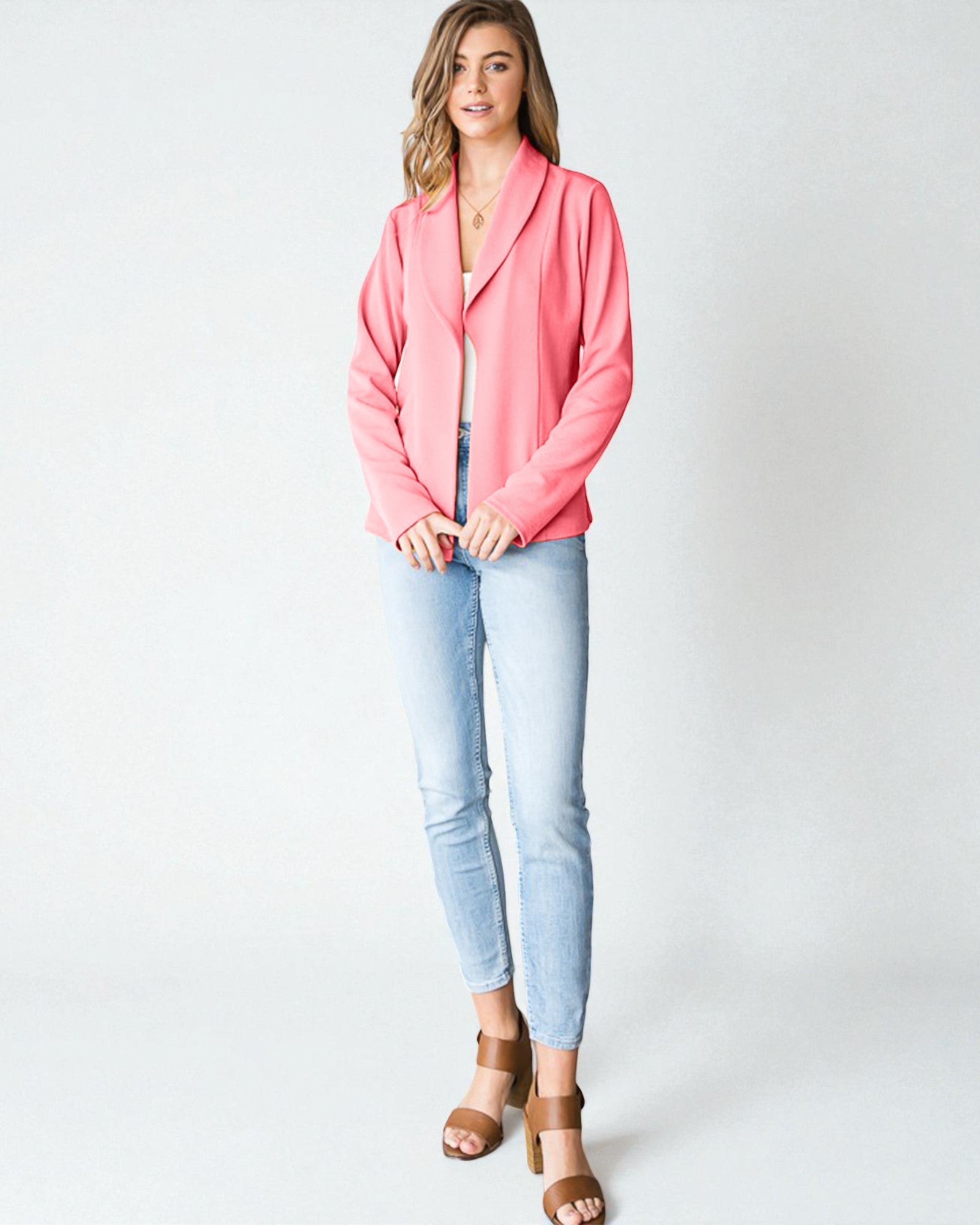 Woman wearing a pink blazer and light blue jeans on a white background