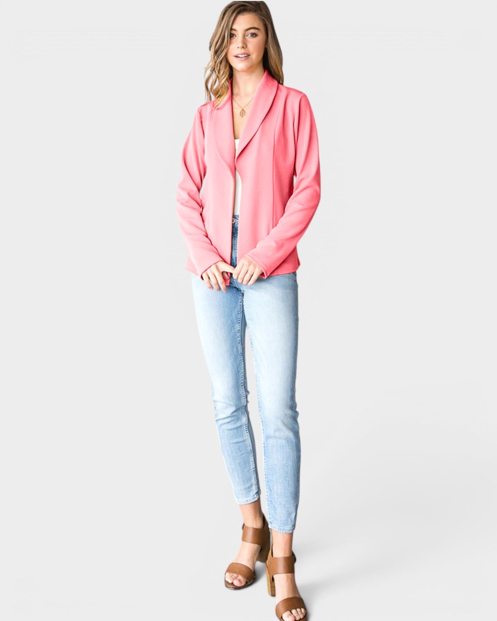 Woman wearing a pink blazer and light blue jeans on a white background