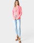 Woman wearing a pink blazer and light blue jeans on a white background