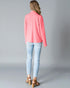 Woman wearing a pink blazer and light blue jeans on a gray background
