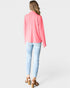 Woman wearing a pink blazer and light blue jeans on a white background