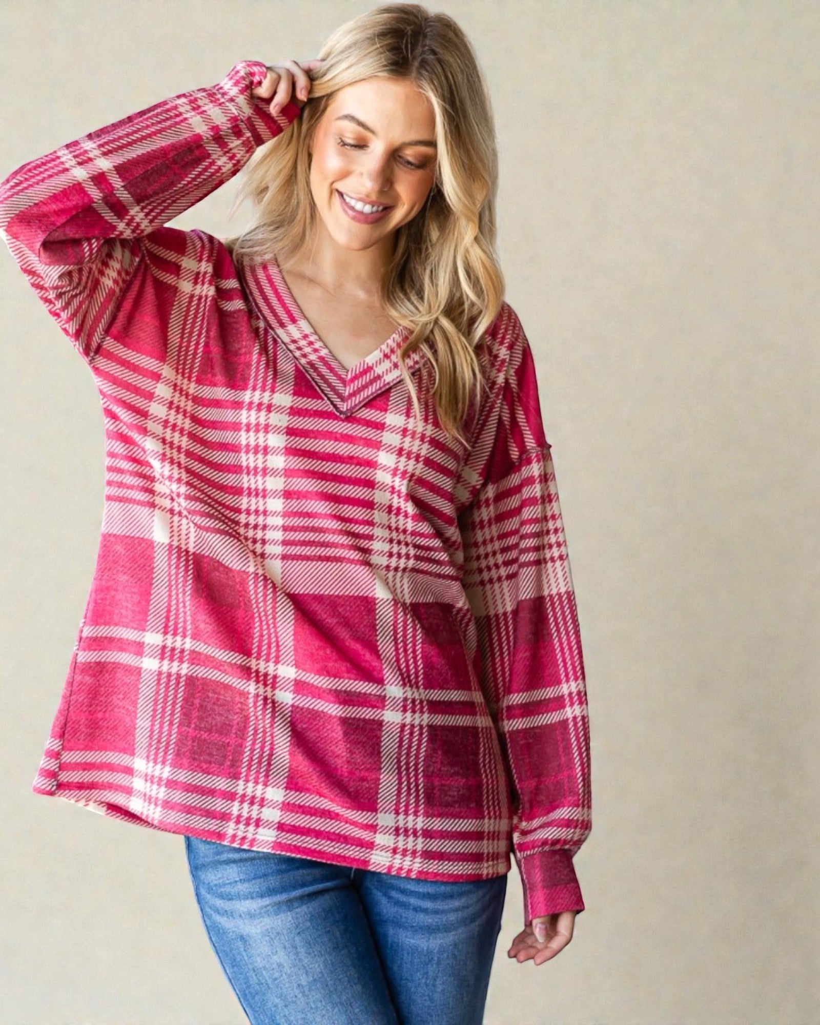 Woman wearing a pink plaid shirt against a beige background