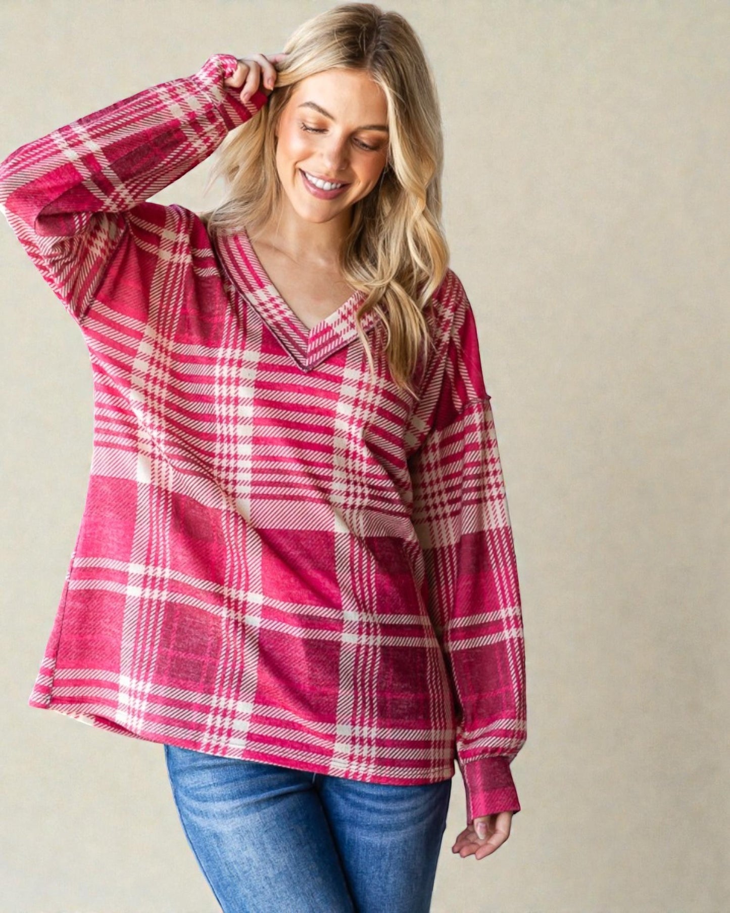 Woman wearing a pink plaid shirt against a beige background