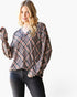 A woman wearing a loose, long-sleeve plaid blouse with a black, white, and red pattern, paired with dark gray jeans, against a plain white background.