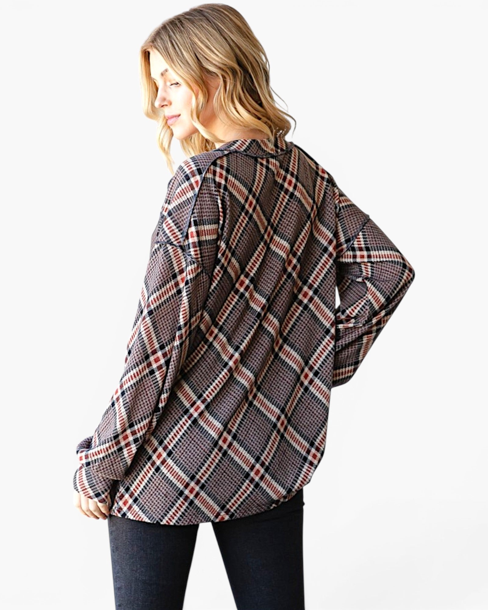 A woman wearing an oversized long-sleeve plaid button-up shirt in black, white, and red, shown from a three-quarters back view against a plain white background.