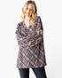A woman modeling a long-sleeve plaid tunic top with a black, white, and red pattern, paired with dark jeans, against a plain white background.