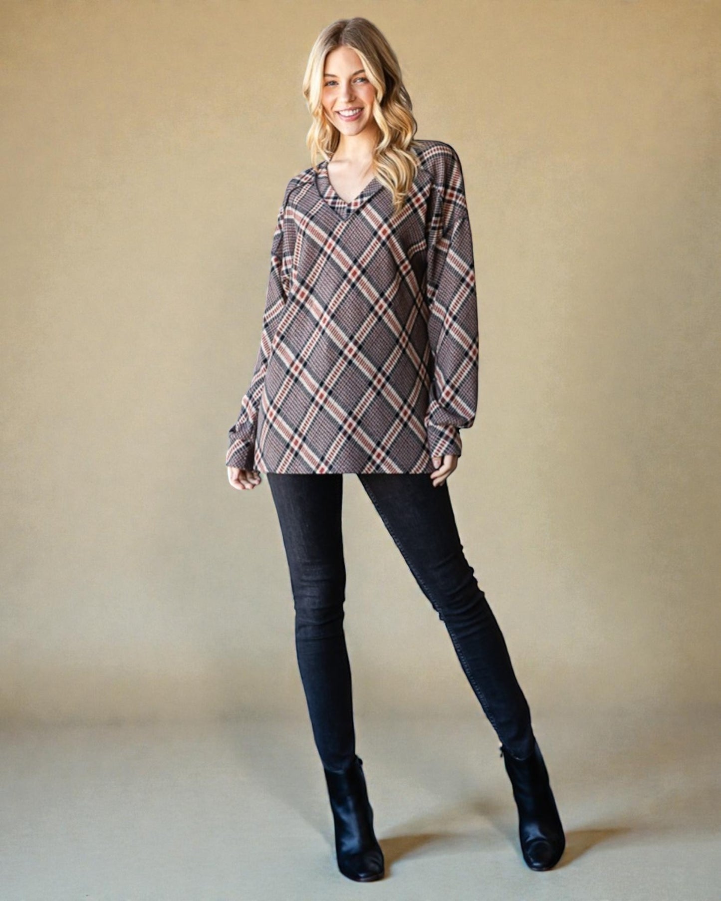 Woman wearing a plaid shirt and black pants against a beige background