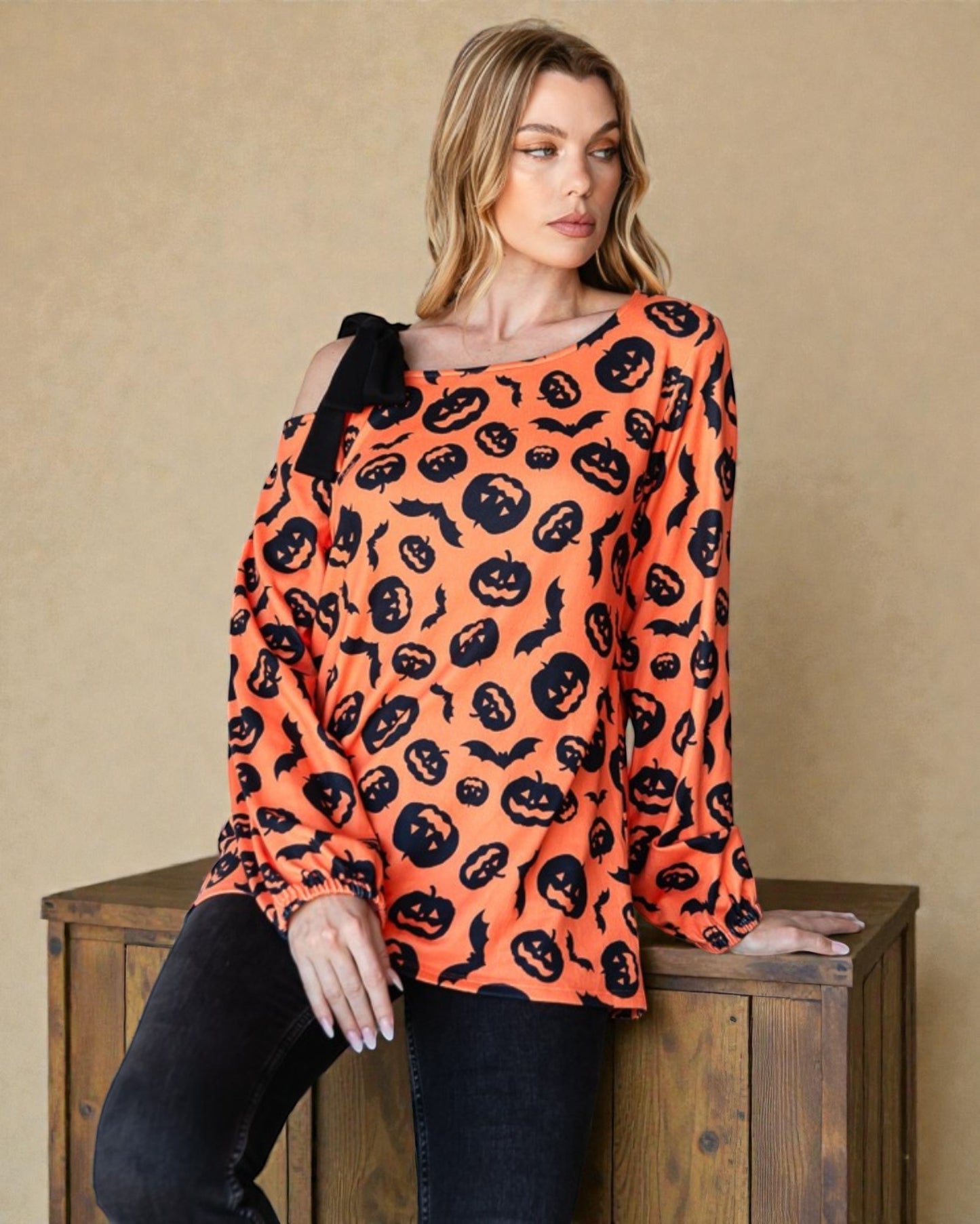 Woman wearing an orange Halloween-themed sweater with black patterns on a beige background