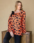 Woman wearing an orange Halloween-themed sweater with black patterns on a beige background