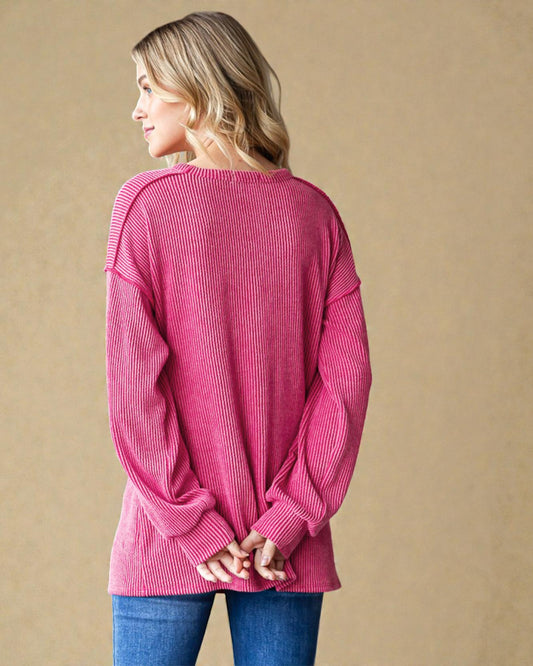 Woman wearing a pink sweater with a knot detail on a beige background