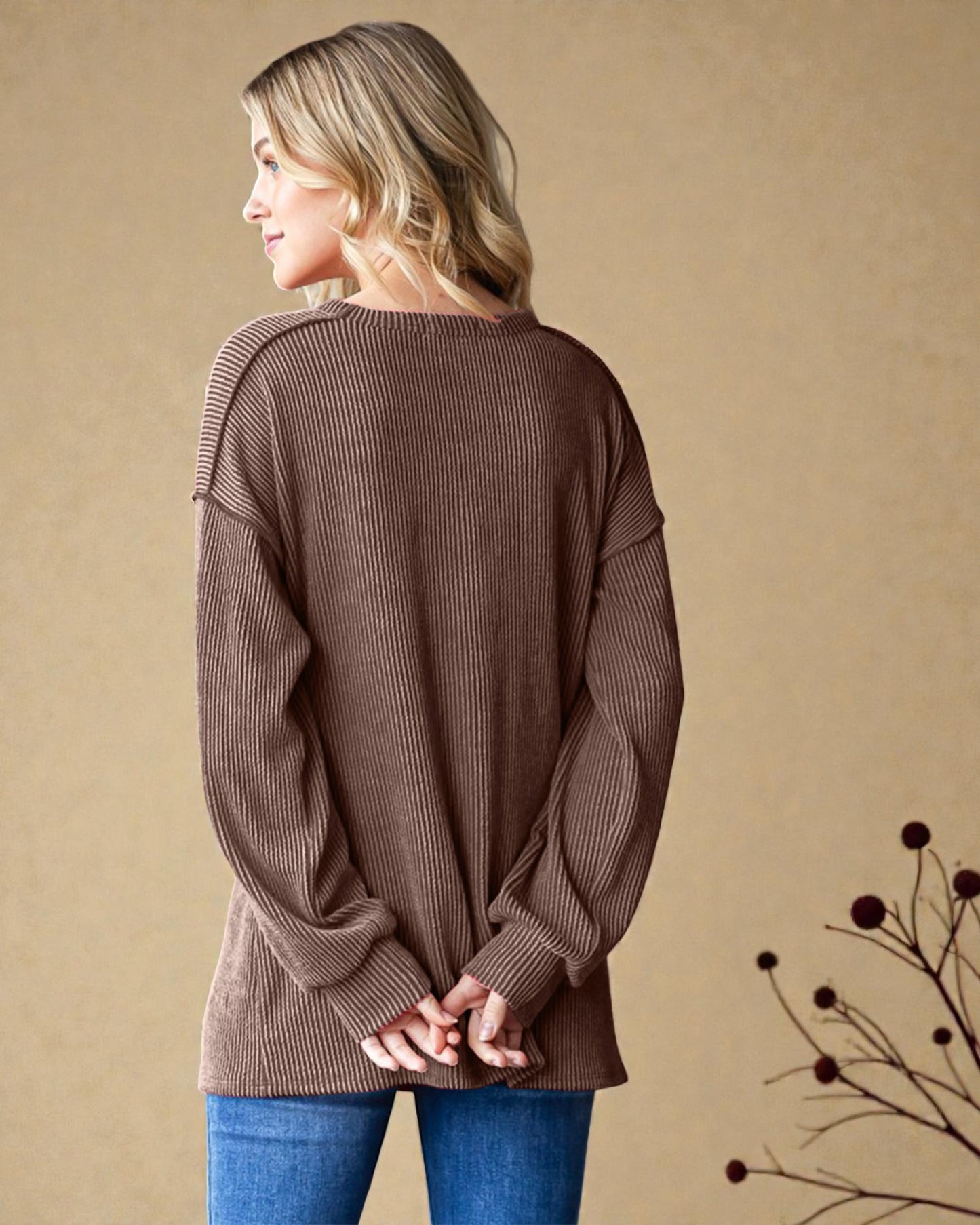 Woman wearing a brown ribbed sweater against a beige background