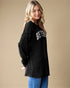 Woman wearing a black sweater with 'Beverly' text on a beige background