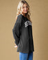 Woman wearing a black jacket with 'Beverly' text on a beige background